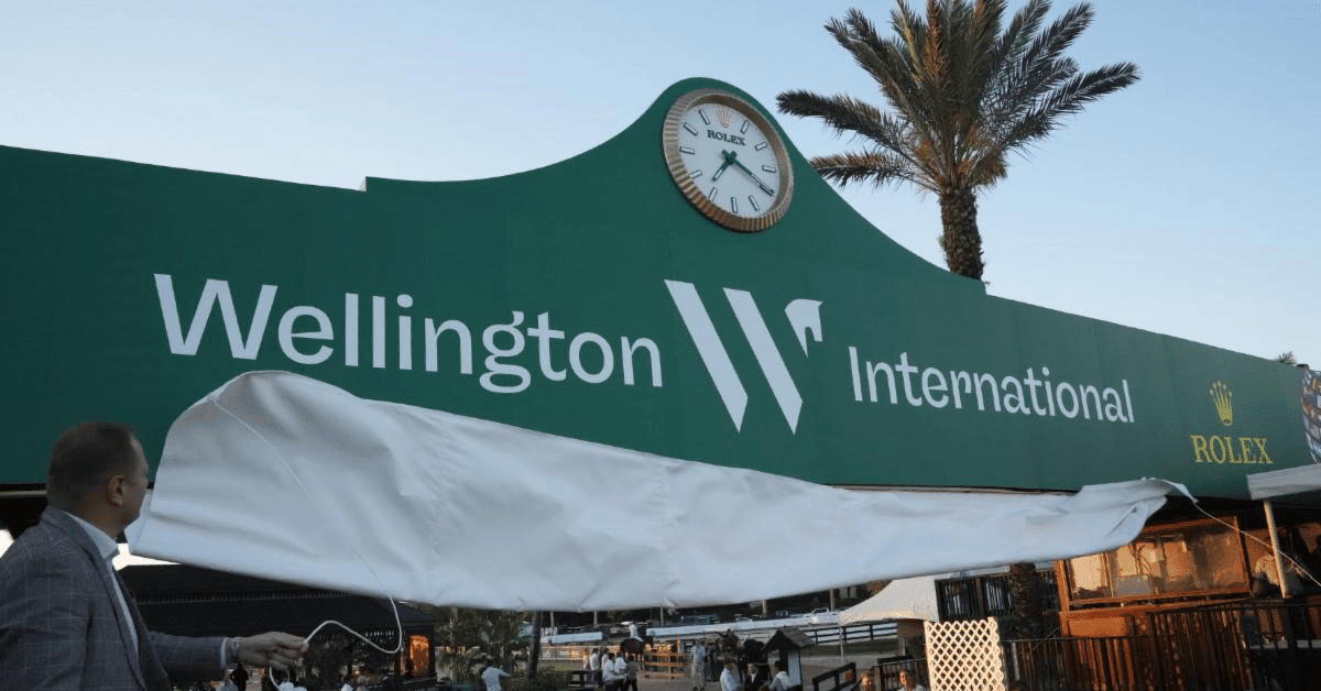 Wellington International sign with palm trees and Rolex logo in background.