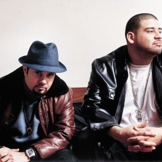 Two men sitting, one with a hat, on Master at Work post on Partybody.