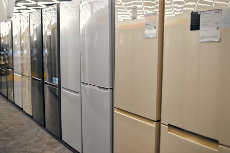 Row of refrigerators in various colors on display in a store.
