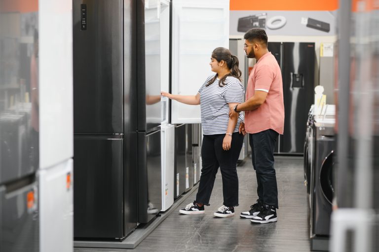 Two people looking at refrigerators in an appliance store