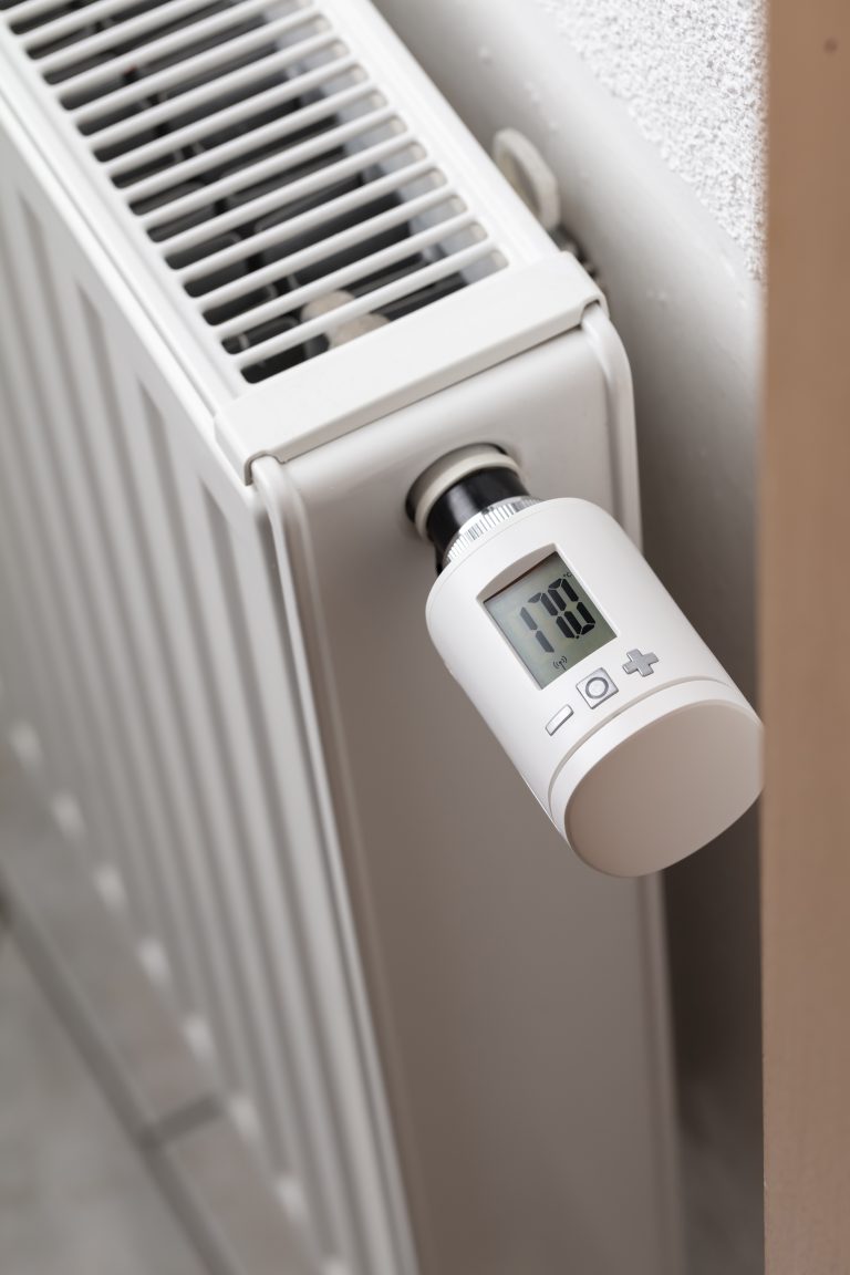 Close-up of a white smart thermostat on a radiator showing 17.0 degrees.