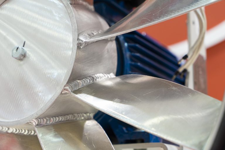Close-up of a metal fan with multiple blades and a blue motor.
