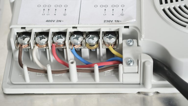 Close-up of electrical wiring connections with colored wires and screws.