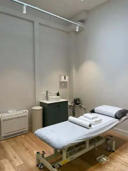 Modern physiotherapy treatment room with massage table and relaxing environment in London.