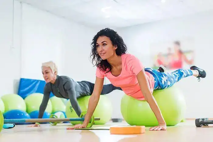 Woman performing physiotherapy exercises on exercise balls.
