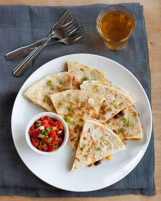 quesadillas on a plate with pico sauce in a small bowl