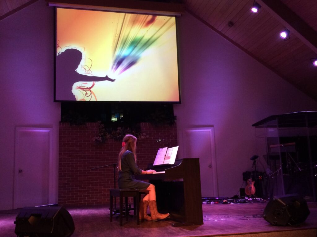 student laying on stage with a colorful slide behind her
