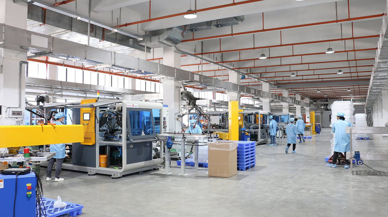 High-tech plastic and glass container manufacturing facility with automated machinery and workers in.