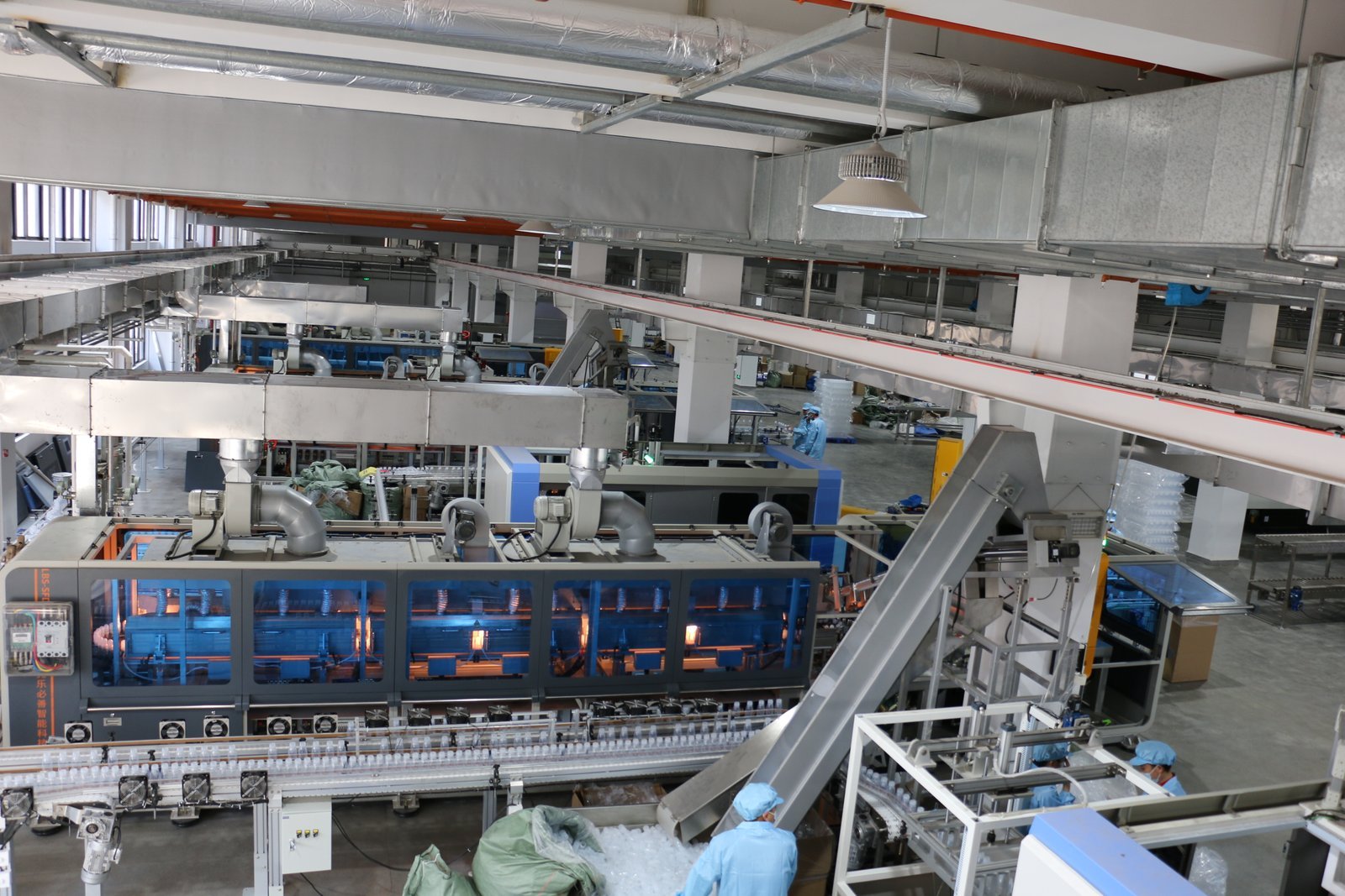 Industrial manufacturing of glass and plastic bottles in a modern factory setting.