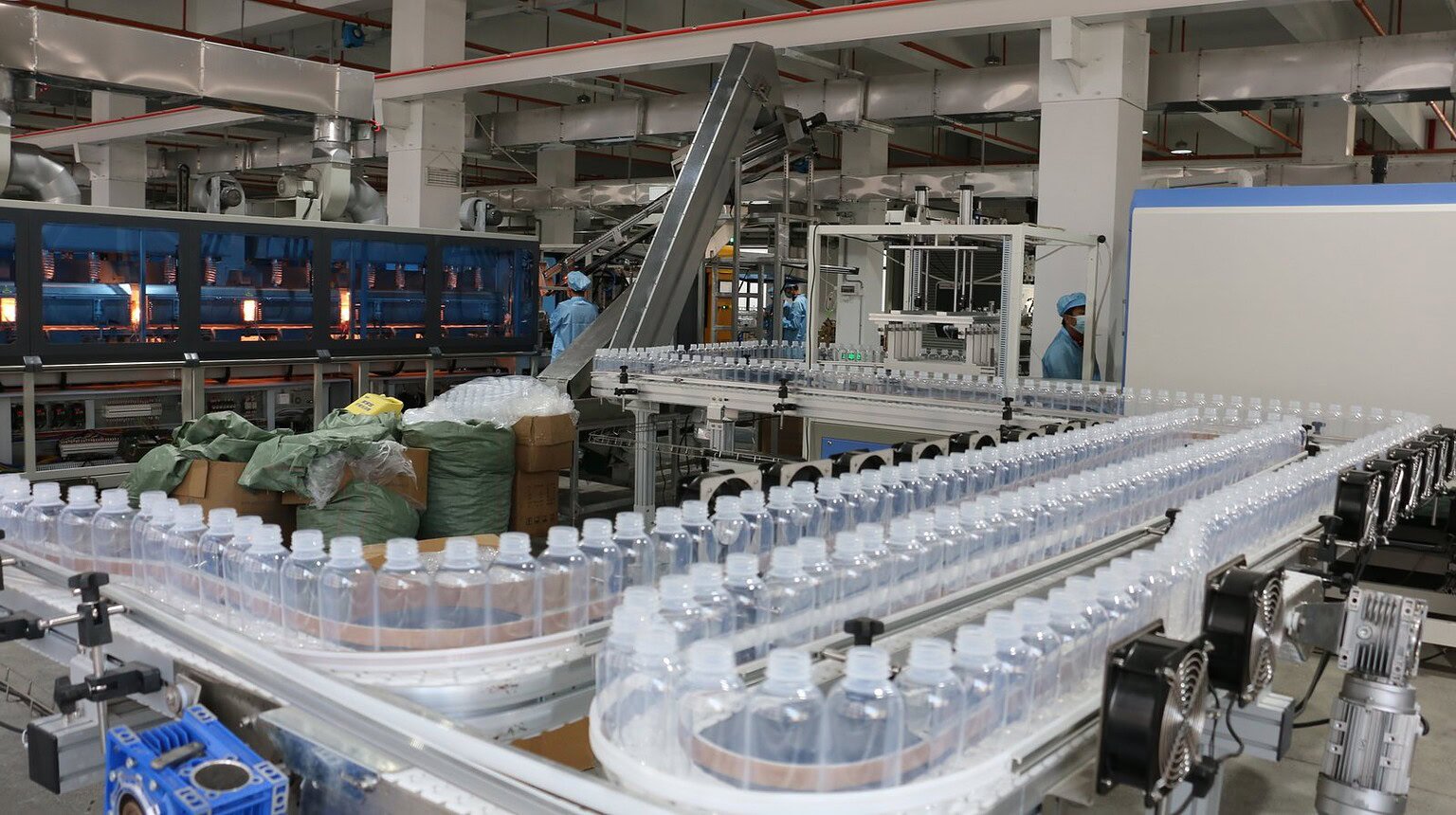 Plastic bottles moving along a conveyor belt in a manufacturing facility.