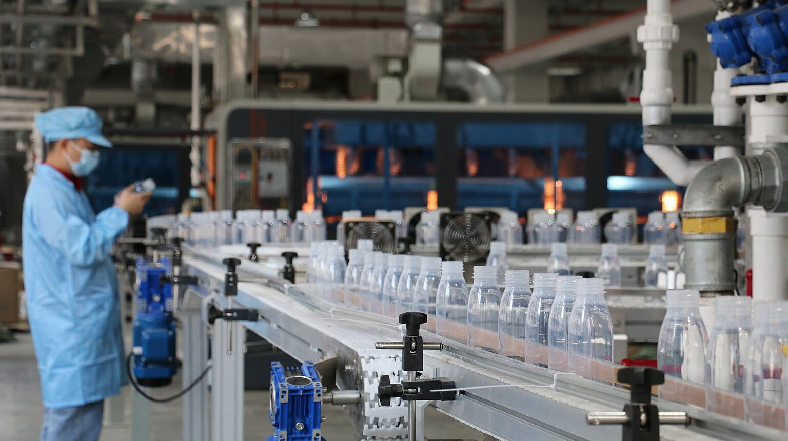 High-speed manufacturing line producing custom glass and plastic bottles in a factory setting.