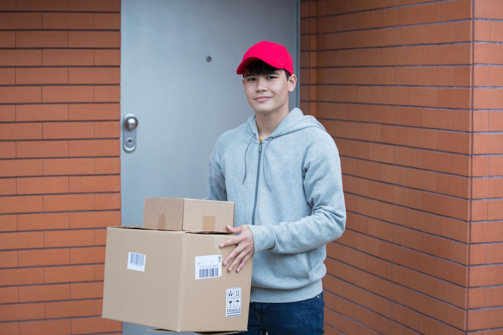 Delivery person holding packages outside a building.