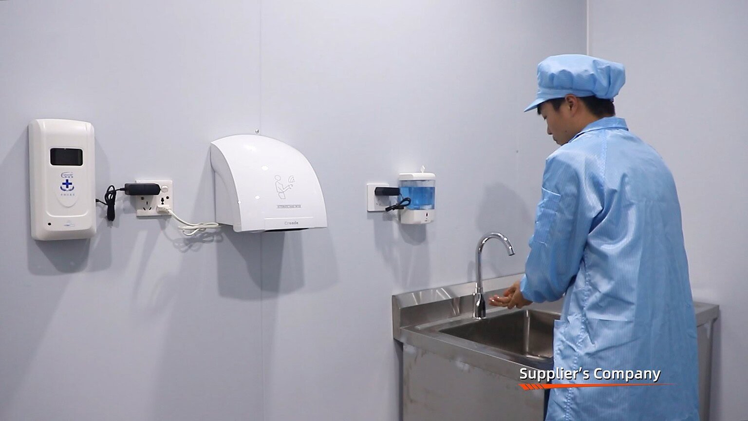 Worker in protective gear handling glass or plastic containers in a clean manufacturing facility.
