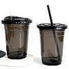 black PET cold cups filled with drinks are placed on the bar counter. PET cups are suitable for juice shops, coffee shops, soft drink shops, and bubble tea shops.