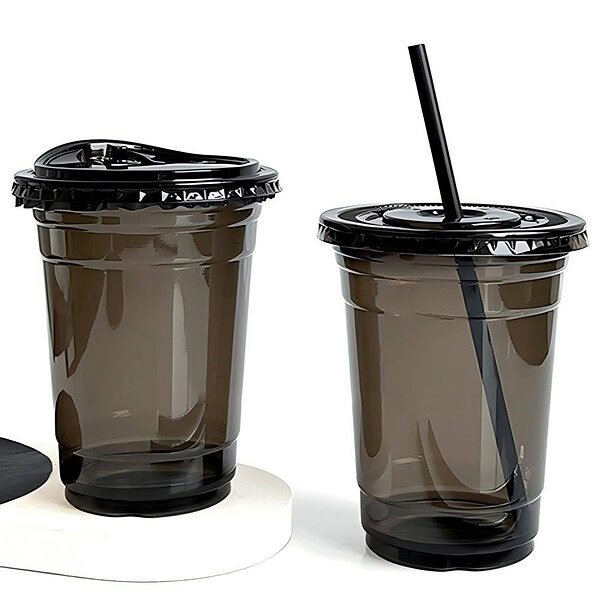 black PET cold cups filled with drinks are placed on the bar counter. PET cups are suitable for juice shops, coffee shops, soft drink shops, and bubble tea shops.