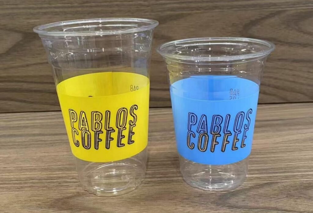 Clear plastic cups with yellow and blue labels for Pablos Coffee.