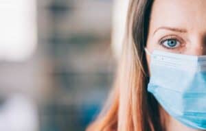 A close up image of a lady wearing a medical face mask.