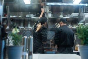 Chefs inspecting kitchen ventilation system for grease build-up.