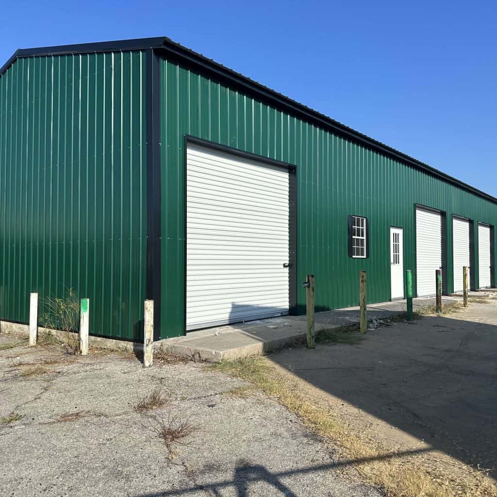 Green metal storage building with multiple roll-up doors in Texas.