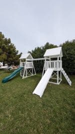 Watch Tower Vinyl playset in backyard with green grass and large tree.