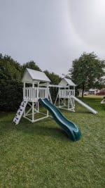 Watch Tower Vinyl playset in backyard with green grass and large tree.