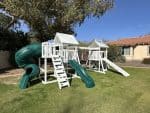 Watch Tower Vinyl playset in backyard with green grass and large tree.