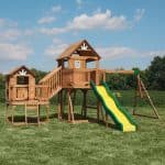 Wooden outdoor playset with slide, swings, and climbing areas for kids in Texas yard.