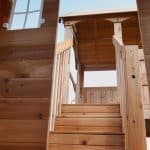 Wooden playhouse with stairs and balcony for kids in Texas outdoor setting.