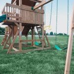 Wooden outdoor playset with swings and slide for kids in Texas backyard.