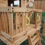 Wooden outdoor playset with stairs and safety railings for kids.