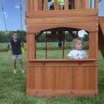Children playing on a wooden outdoor playset in Texas backyard.
