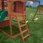 Wooden outdoor playset with swings and slide for kids in Texas backyard.