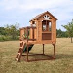Wooden playhouse for kids with slide and balcony in outdoor yard.