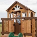 Child playing with a black ball in a wooden playhouse in Texas.