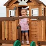 Young girl playing in a wooden outdoor playhouse in Texas.