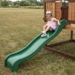 Young girl playing on a green slide at Echo Heights Playhouse in Texas.