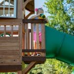 Child looking through binoculars on outdoor playset in Texas.