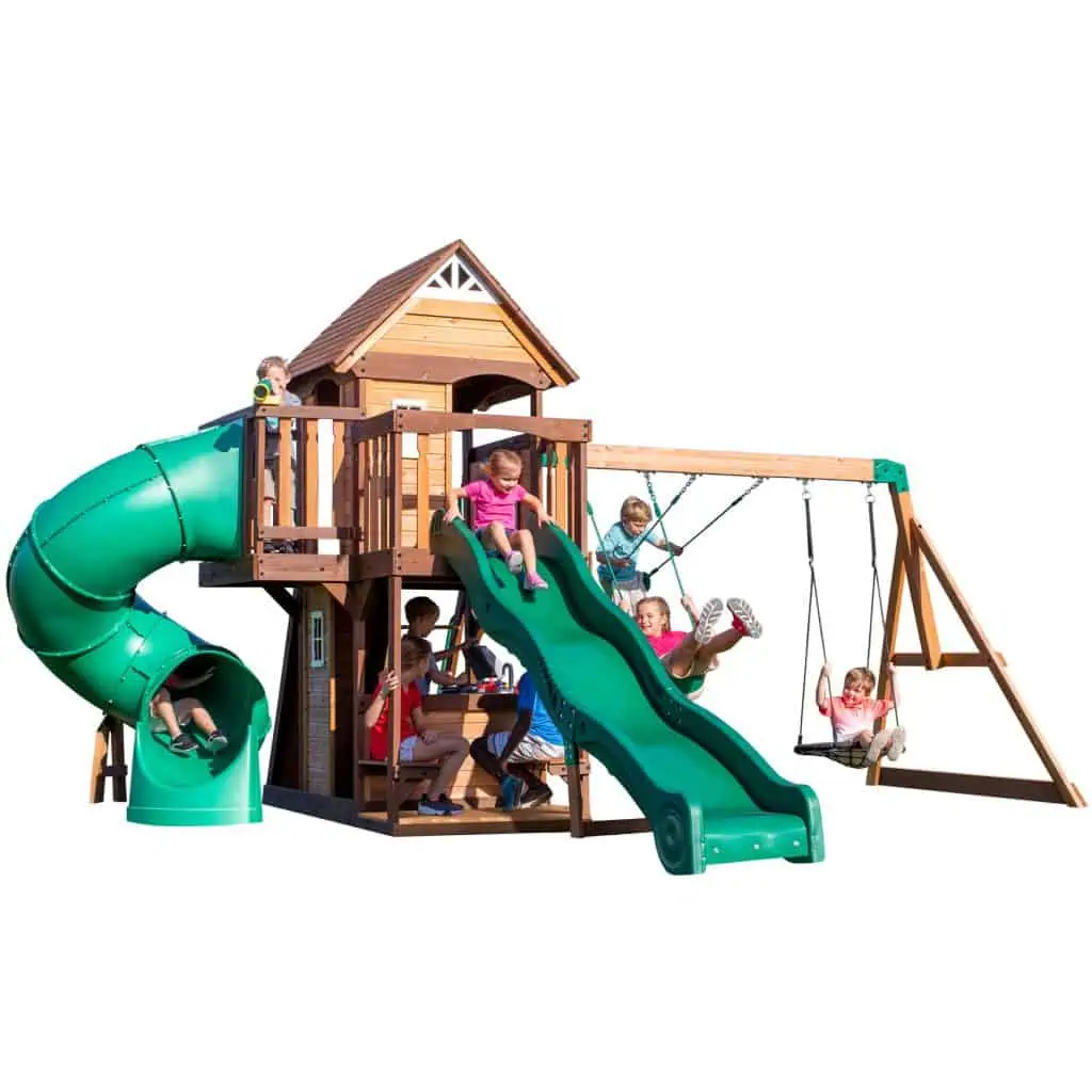 Children playing on a Cedar Cove Swing Set with slide and swings in a backyard.
