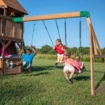 Kids playing on Cedar Cove swing set in backyard.