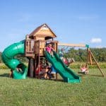 Children playing on Cedar Cove swing set with slides and swings in Texas backyard.