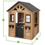 A technical dimension diagram shows a wooden children's playhouse isolated on a white background. The structure is built from light-toned wood with a dark gray gabled roof and black accents, including a small half-door, window frames, and two flower box holders. Green measurement lines and circles indicate the physical dimensions of the playhouse: a total height of 55", a front width of 42", and a side depth of 46". Inside the open structure, a small play sink with a faucet is visible, along with a wall-mounted toy phone. An oval Backyard Discovery logo is located on the bottom right front panel.