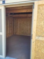 An eye-level shot looking through the open doorway into the interior of a newly constructed wooden shed.