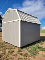 Gray 10×12 lofted barn shed with white trim and double barn-style doors displayed on a gravel lot.