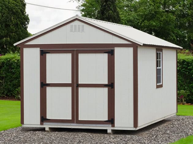 Painted utility shed with double doors, transom windows, and contrasting trim in an outdoor display area.
