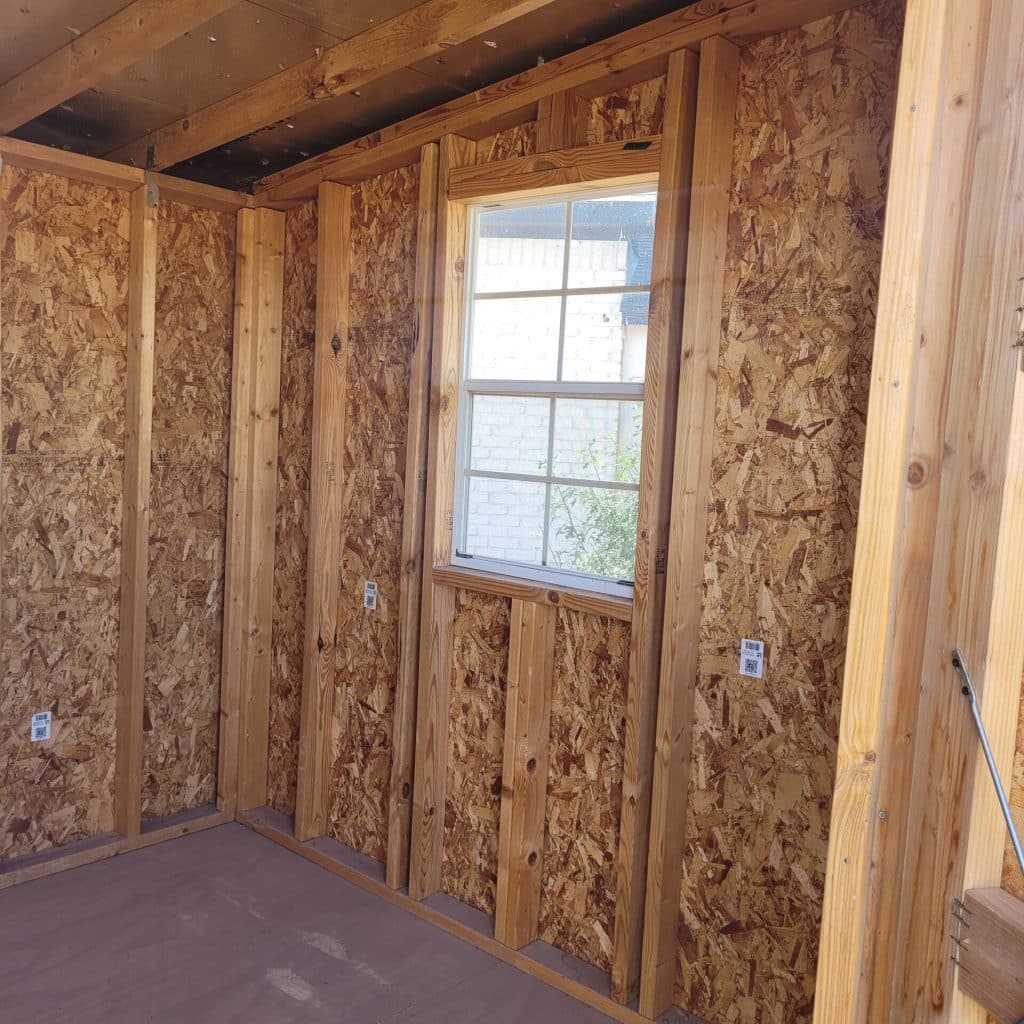 Interior view of an 8x12 red portable building showing unfinished wood framing and open floor space.