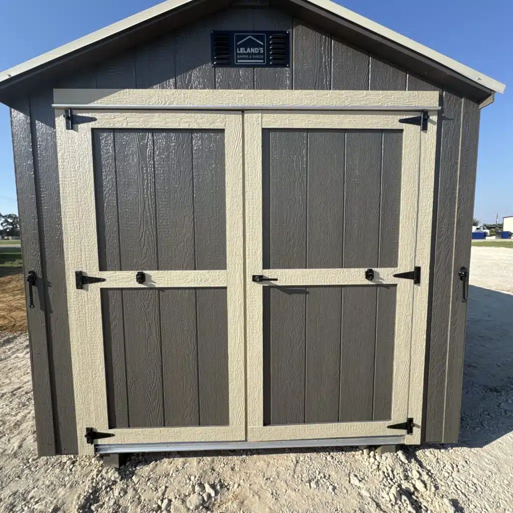Beige 8x12 wooden shed with contrasting trim and double front doors, shown in an outdoor display area.
