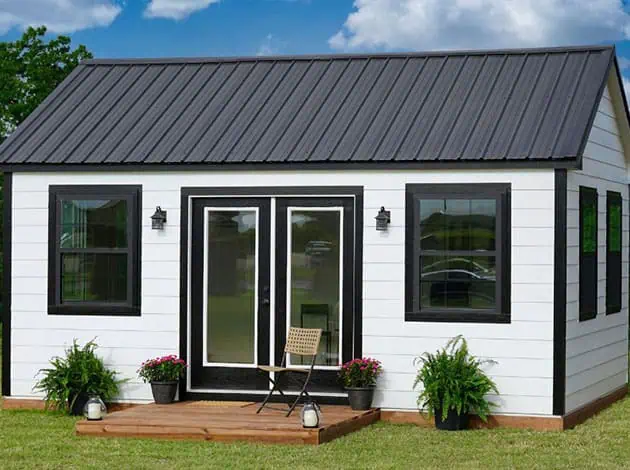 Charming painted wood shed with white trim and blue siding used as a stylish backyard addition.