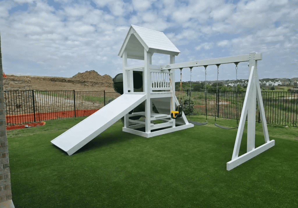 White vinyl playset with a covered tower, attached slide, and lower play area.