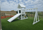 White vinyl playset with a covered tower, attached slide, and lower play area.