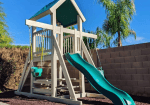 White and teal vinyl playset with a tower, green slide, and climbing structure.